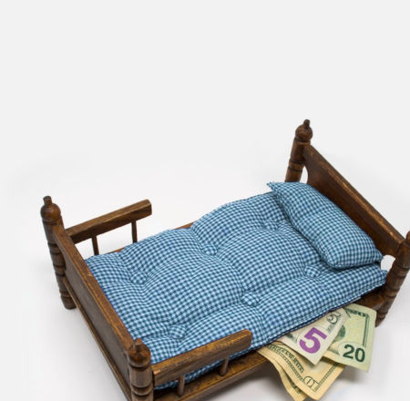 A miniature mattress with money hidden underneath it